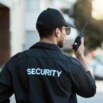 Охрана ЖК PRIME GUARD: безопасность жилых комплексов 24/7 для жителей и управляющих компаний Radio, man and a security guard or safety officer outdoor on a city road for communication. Back of a person with a walkie talkie on urban street to report crime for investigation and surveillance